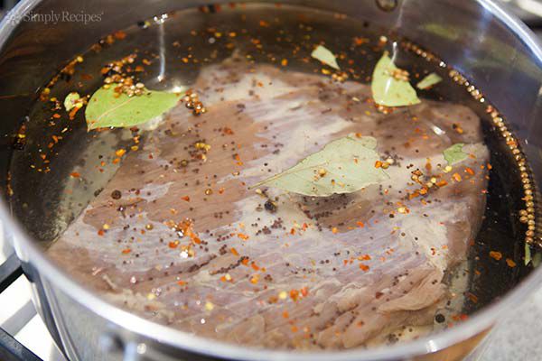 A submerged cut of beed in a pot with herbs and spices thrown in 