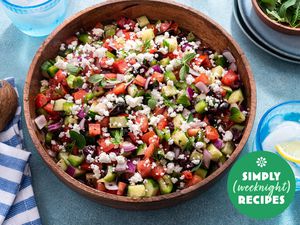 A colorful Greek salad in a wooden bowl on a blue table