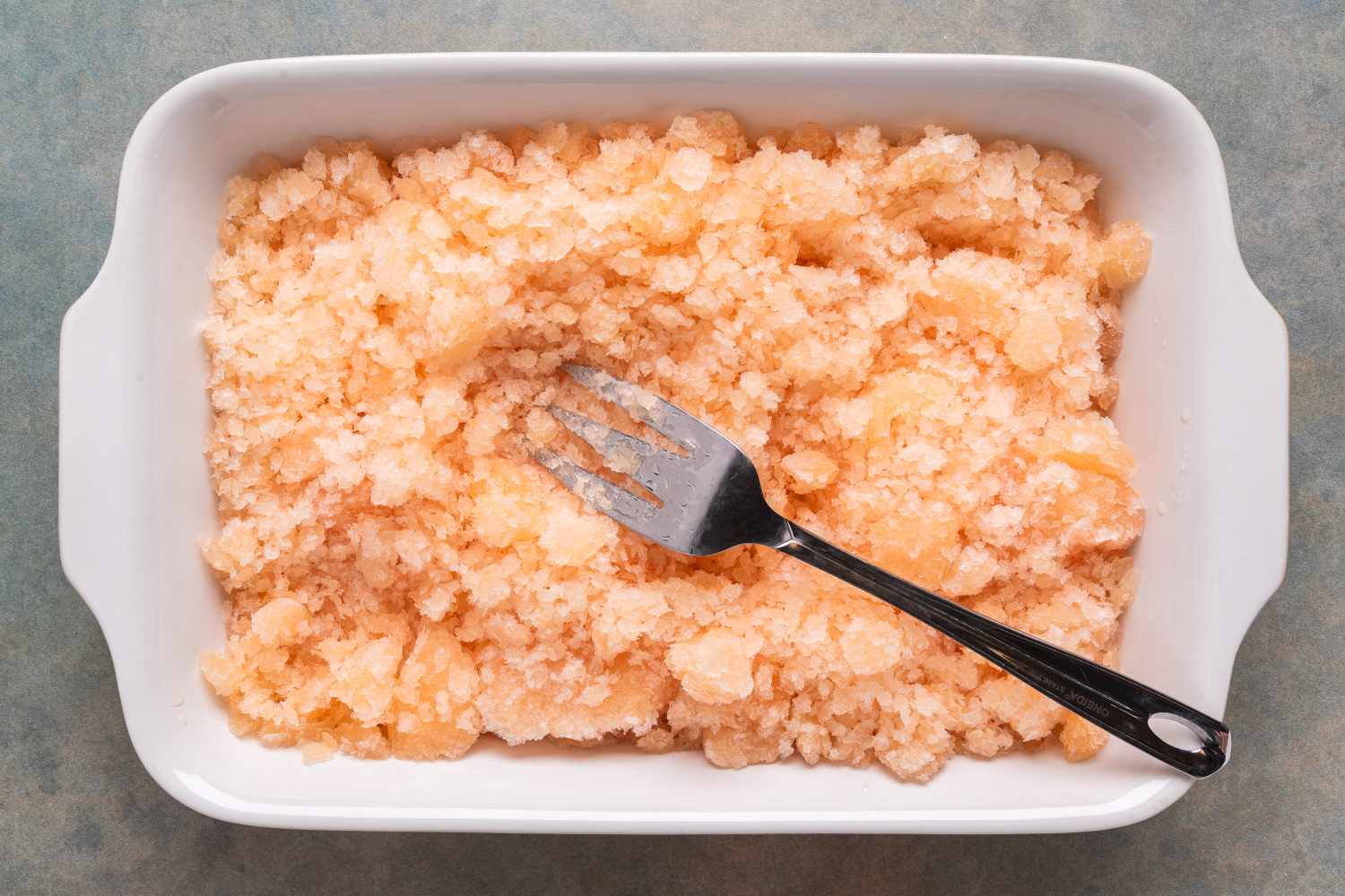 Sparkling grapefruit granita in a white dish served with a fork
