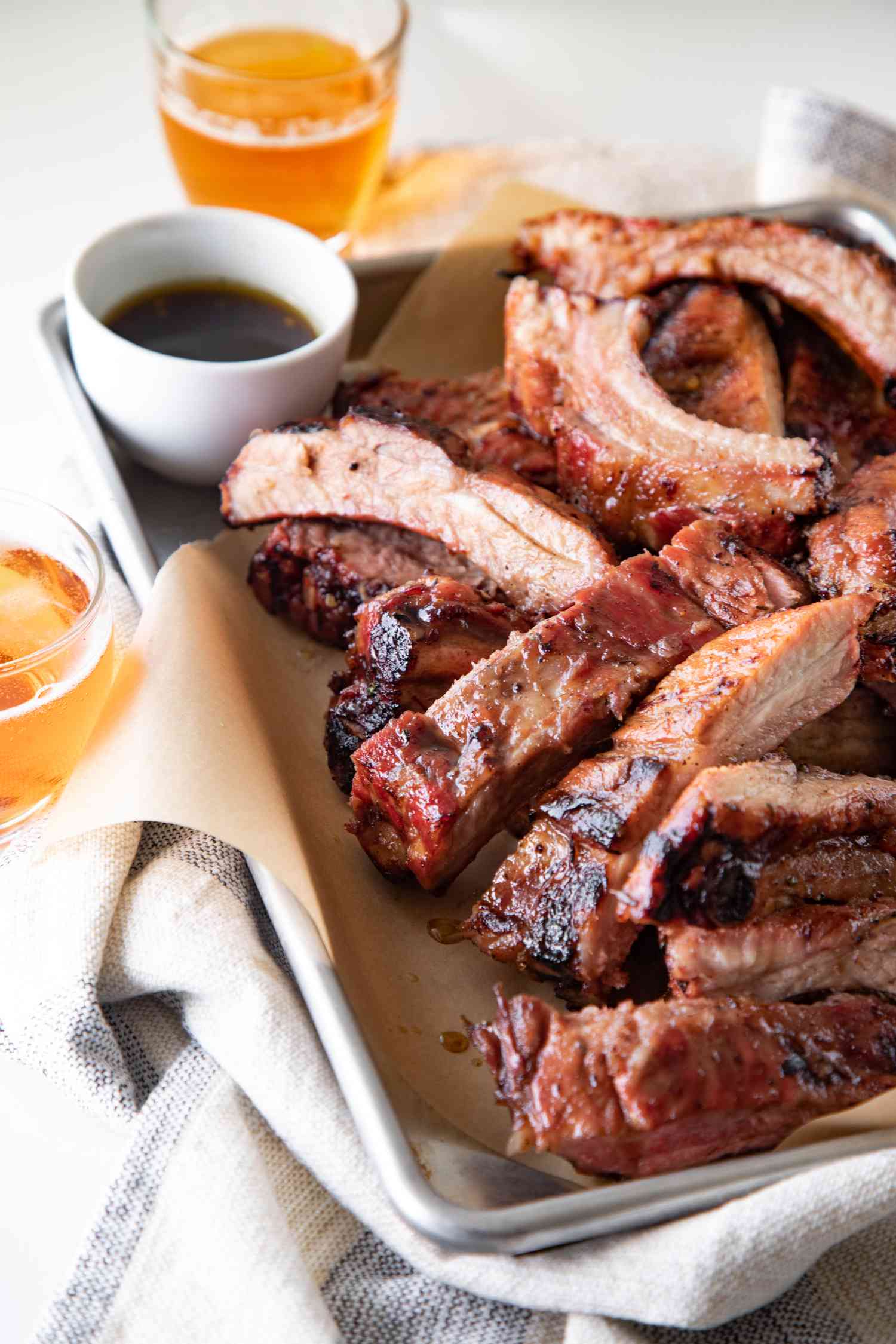 A parchment lined baking sheet with cut ribs from a grilled ribs recipe.