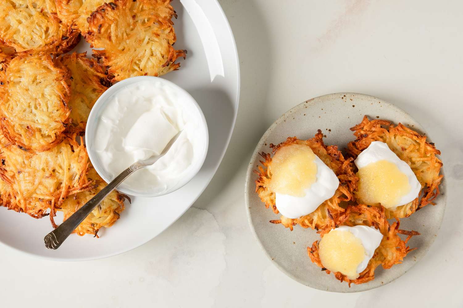 Latkes served with sour cream and applesauce on plates