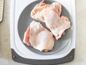 Plate of Boneless Chicken Thighs on a Cutting Board and on the Counter Next to It, a Knife