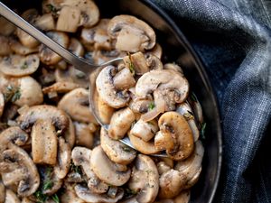 sautéed mushroom in black bowl scooped with spoon