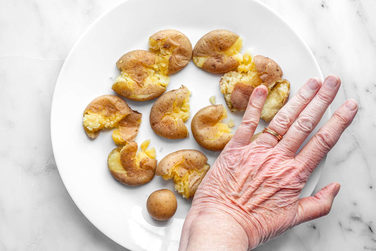 Hand Smashing Potatoes on a Plate 