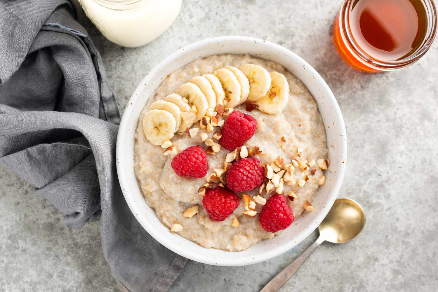 Overhead shot of a bowl of oatmeal topped with banana, rasperries and chopped nuts