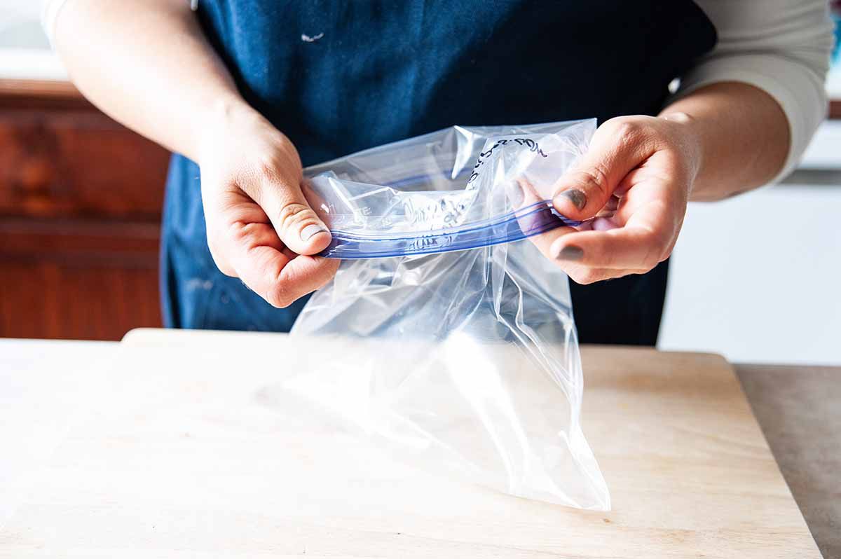 Marinated Chicken - hands rolling down a zip loc bag