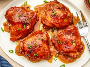 Overhead view of shoyu chicken on a white serving platter with a large serving fork
