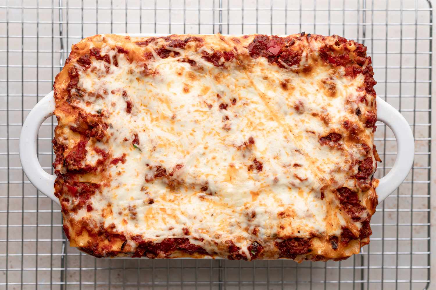 Overhead view of a pan of lasagna cooling on a rack.