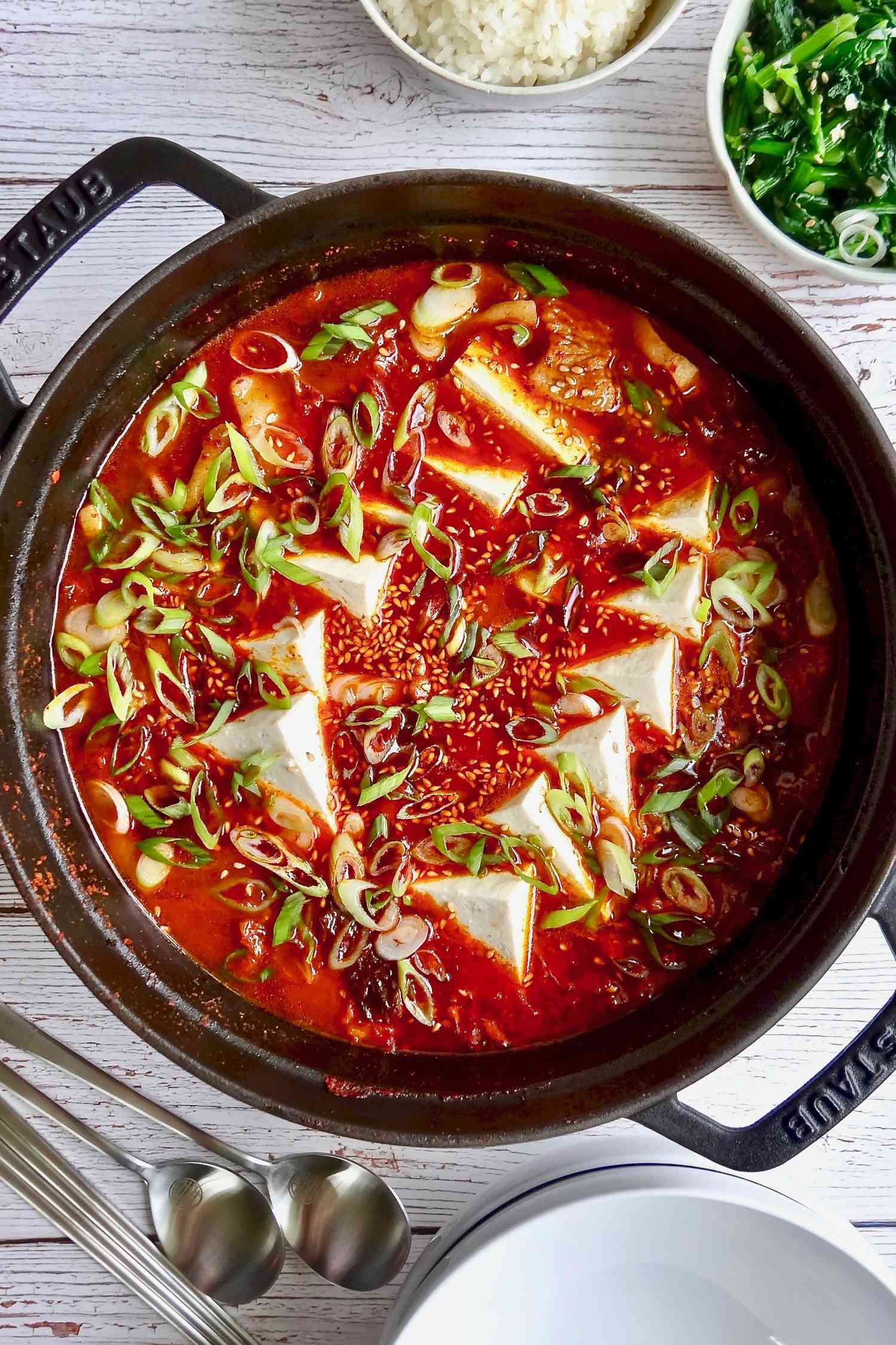 Overhead view of a dutch oven with pork belly and kimchi jjigae inside.