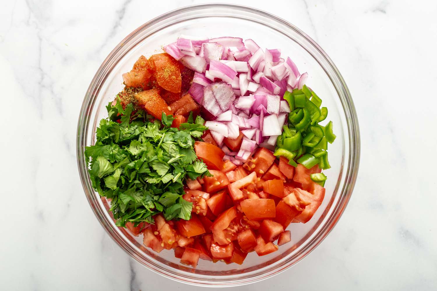 Ingredients to make fresh salsa in a glass bowl.