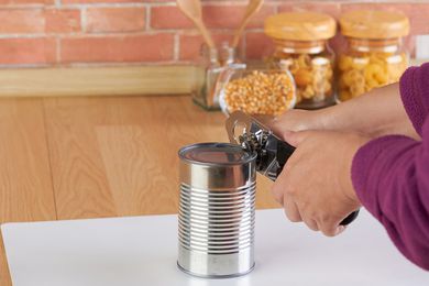 Woman opening a can of corn