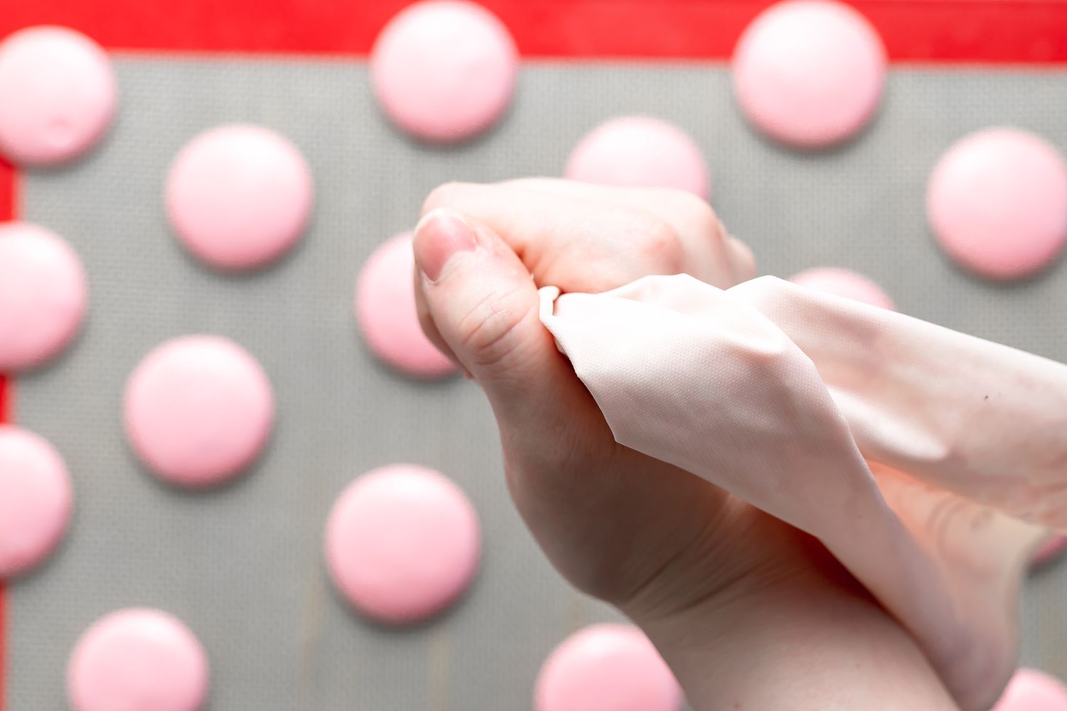 Piping macaron shells onto a silicone baking mat.