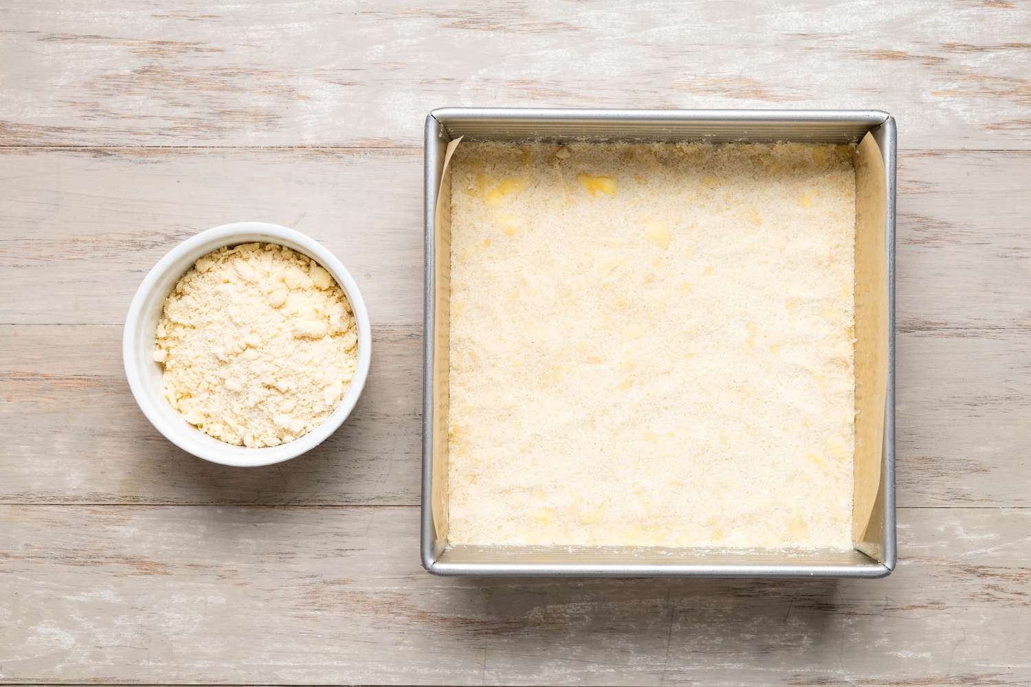 Peach pie par dough patted into a parchment-lined square pan
