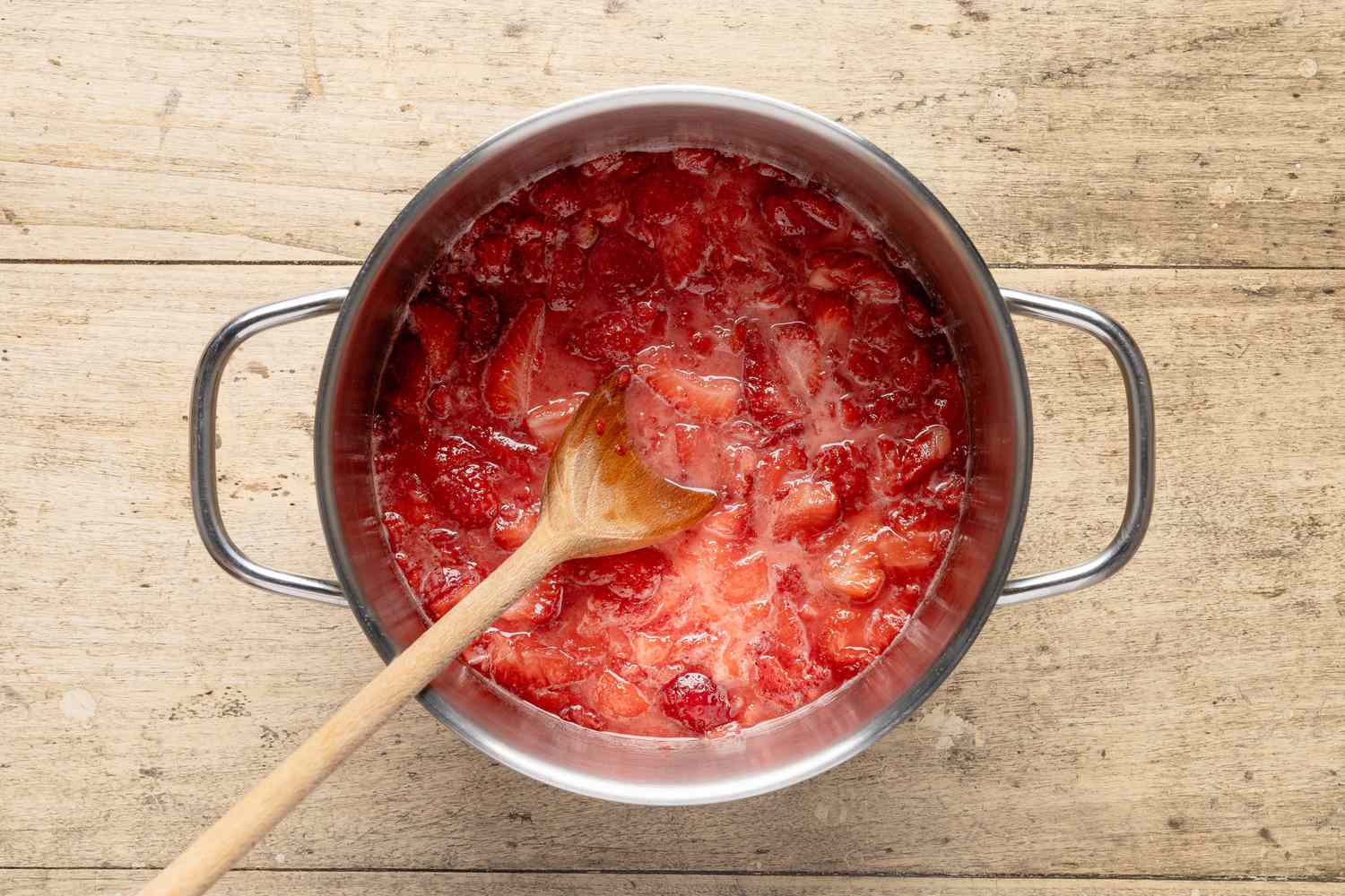 mashed strawberry, sugar, and cornstarch slurry cooked together in a pot for fresh strawberry pie recipe