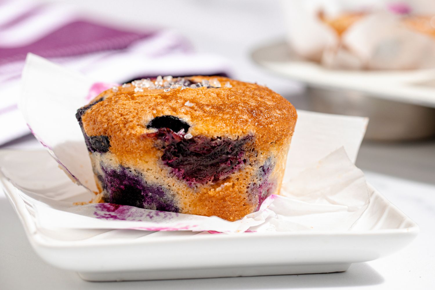 A tray with a blueberry muffin placed on parchment paper