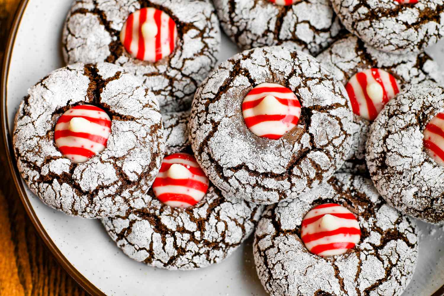 Chocolate crinkle cookies topped with red and white striped candy arranged on a plate