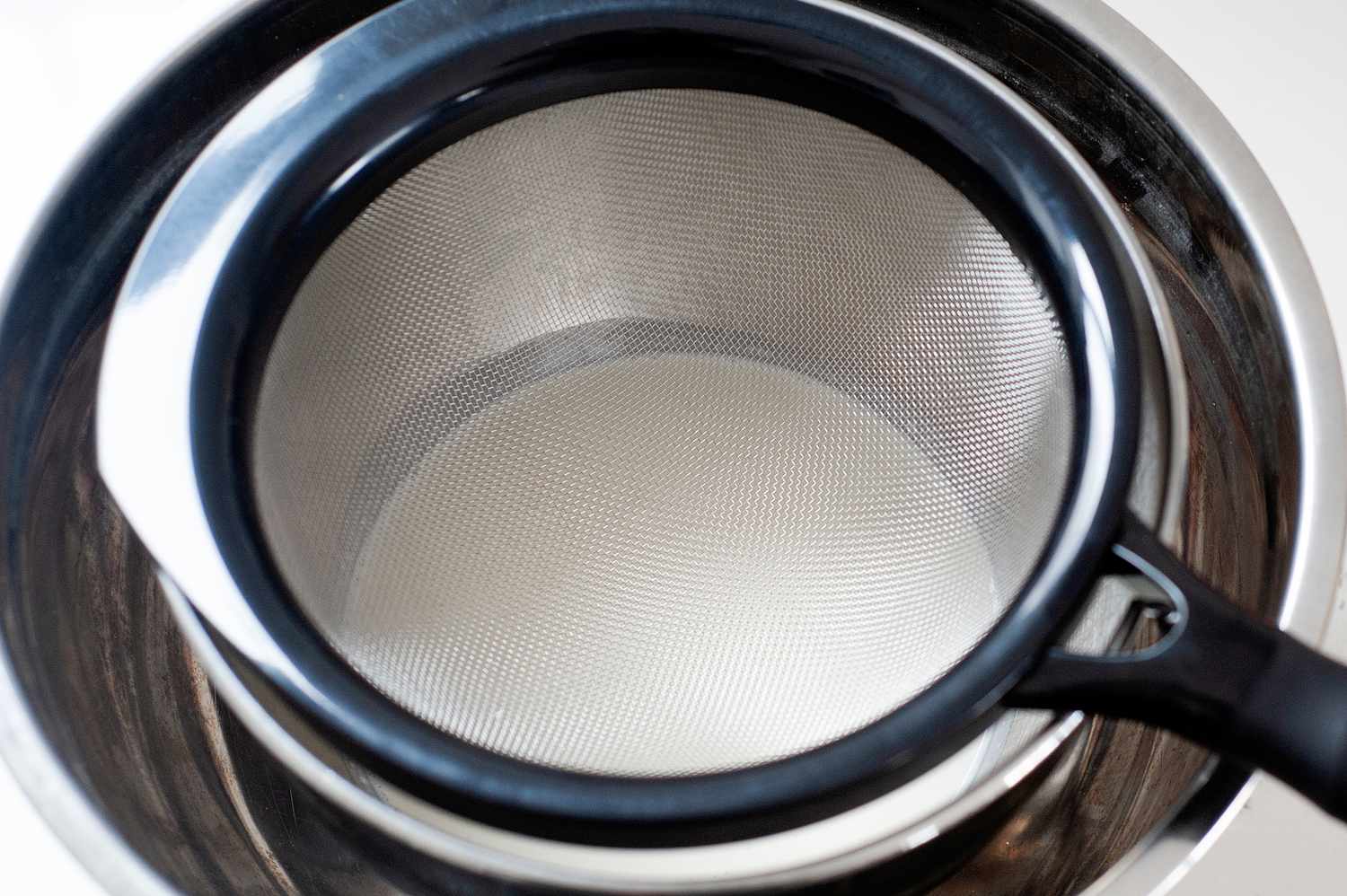 Heavy cream in an ice bath with a strainer set on top to make a butter pecan ice cream recipe.