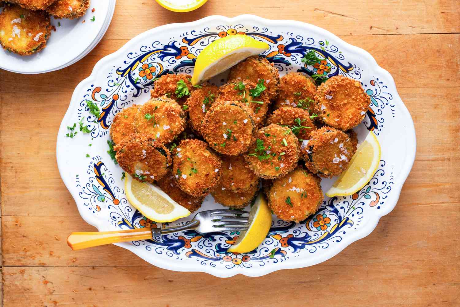 Fried Zucchini on a Platter with Lemon Wedges and a Fork