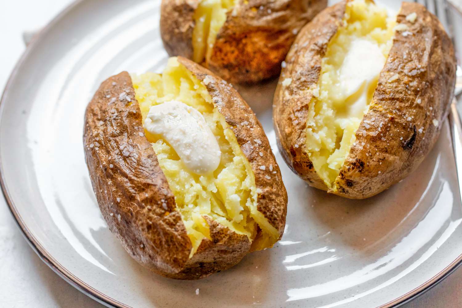 Microwave Baked Potatoes Topped with Butter on a Plate