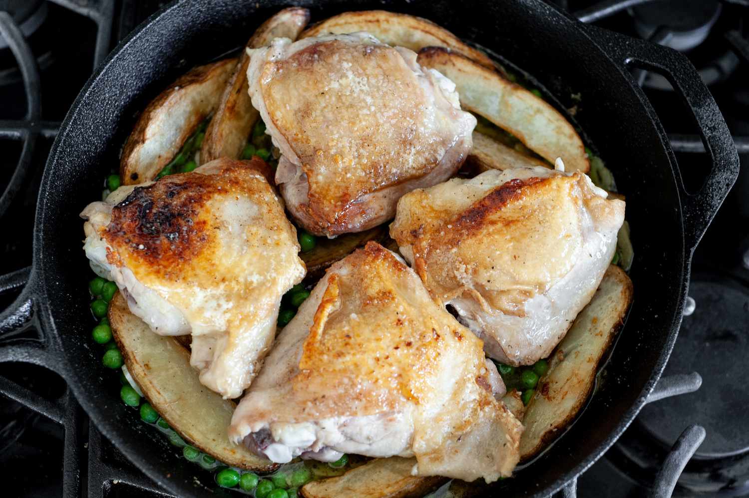 Peas, Garlic, and Sauce Layered with Potatoes and then Chicken in Cast Iron Skillet