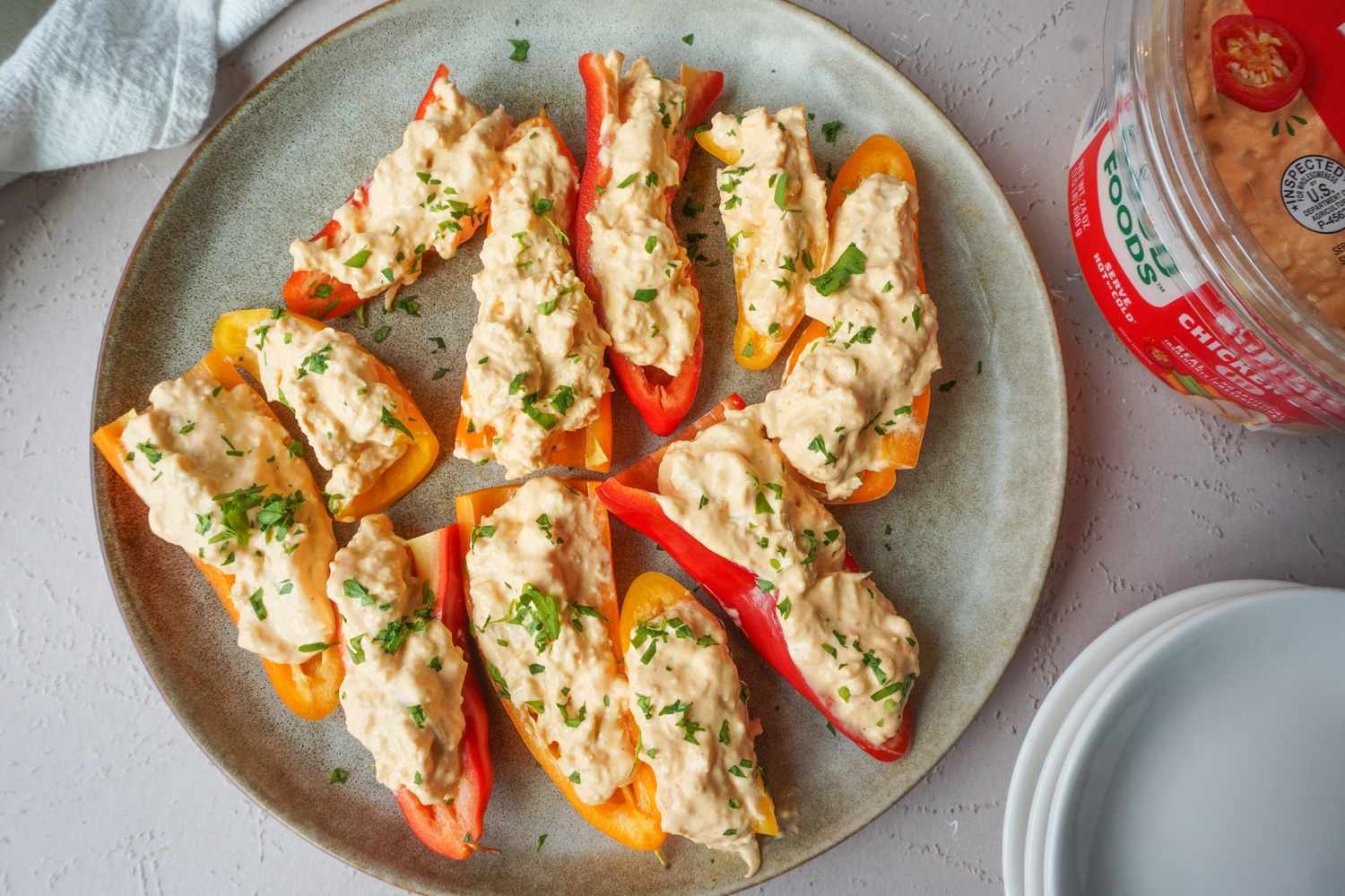Sliced mini bell peppers filled with a creamy mixture garnished with herbs served on a round plate