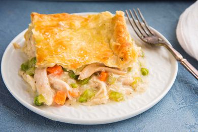 A square slice of the best Chicken Pot Pie is on a plate and the shredded chicken and vegetable filling is visible.