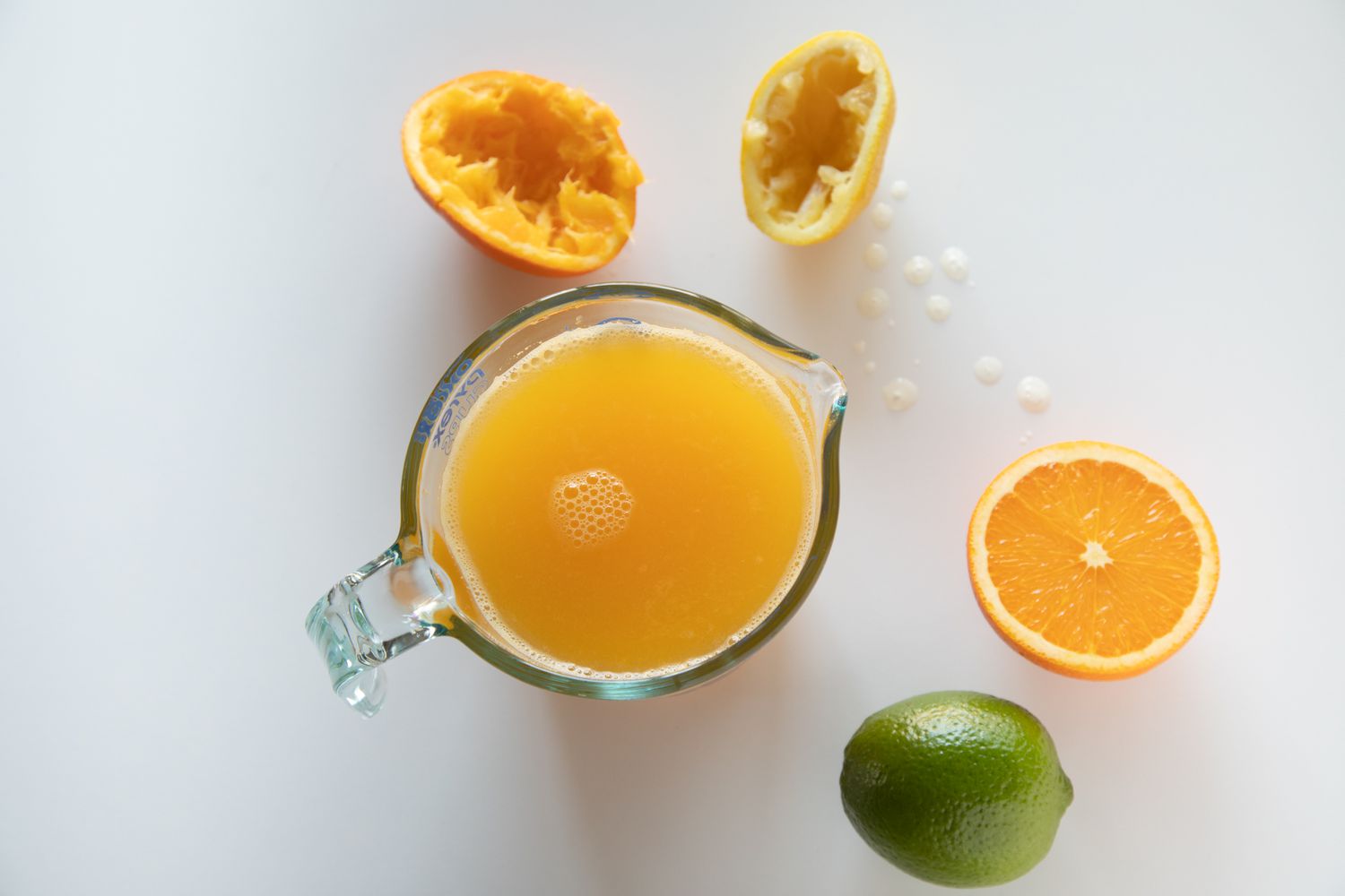 Fresh squeezed orange juice in a pitcher with oranges and a lime for a pork rib marinade.