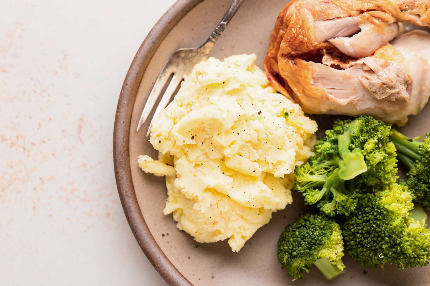 A plate with the best mashed potatoes next to broccoli and chicken.
