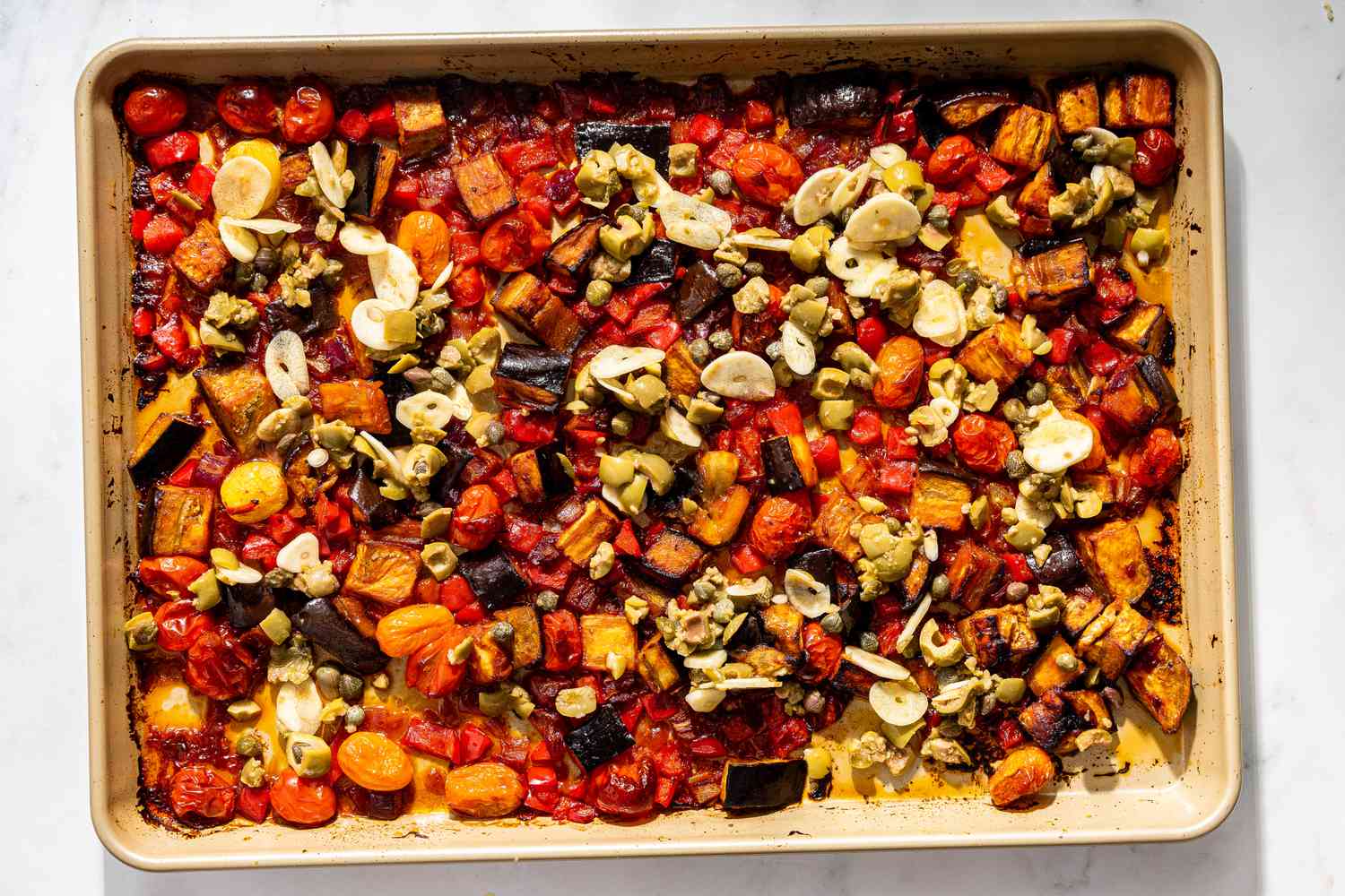 garlic, capers, and olives in a sheet pan for caponata pasta recipe