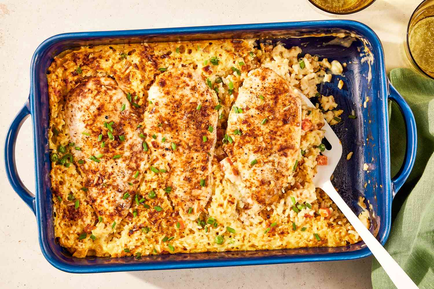 no-peek chicken in a casserole dish at a table setting with two glasses and a table napkin