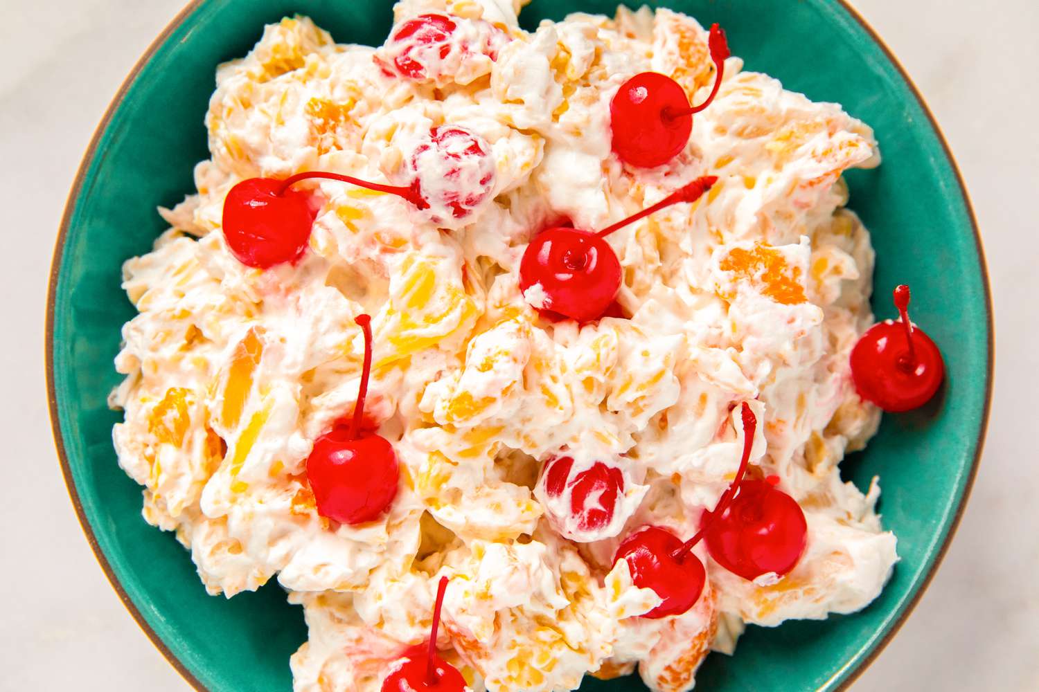 Bowl of creamy salad garnished with cherries