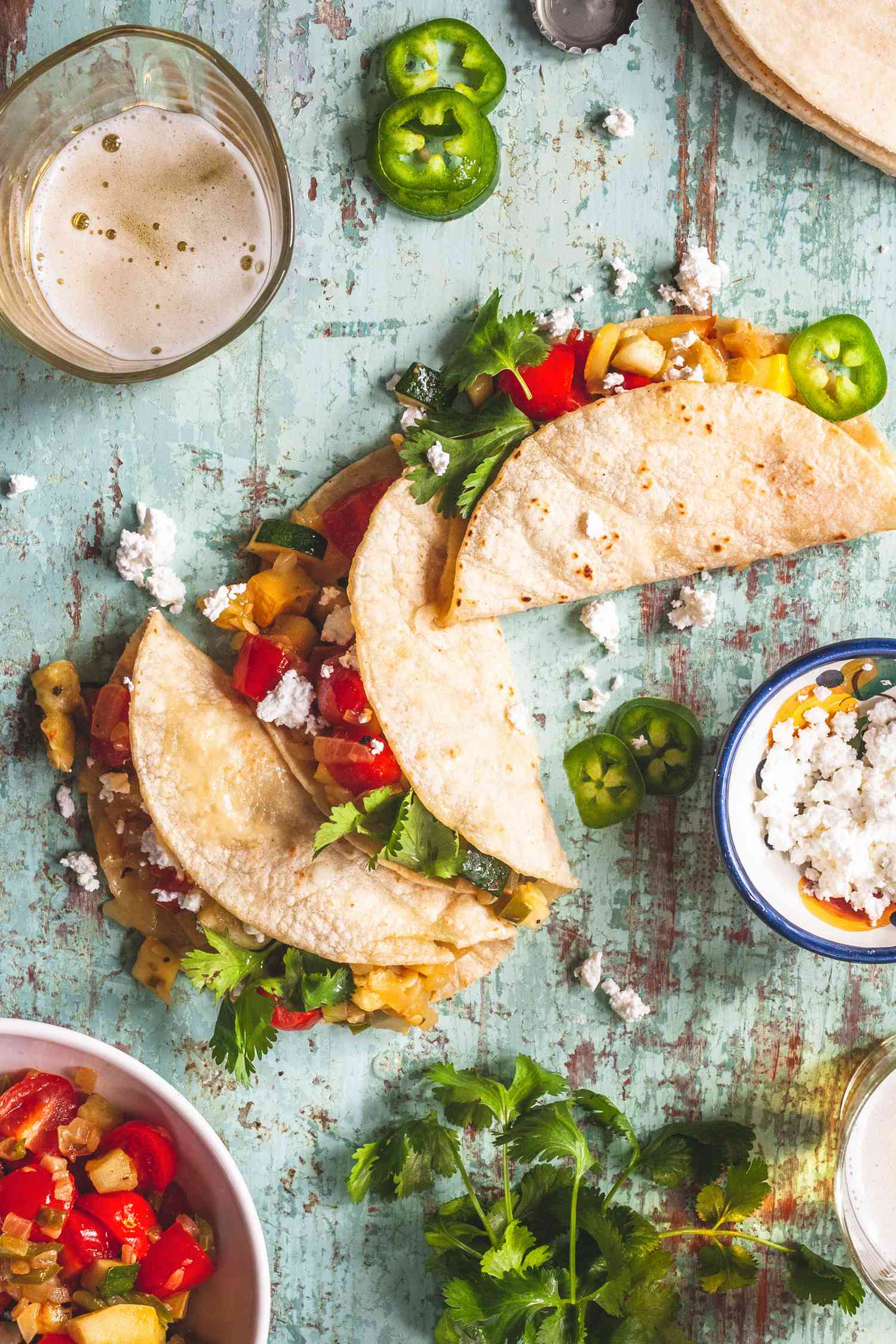 Overhead view of three vegetarian tacos with vegetables visible in the tacos.