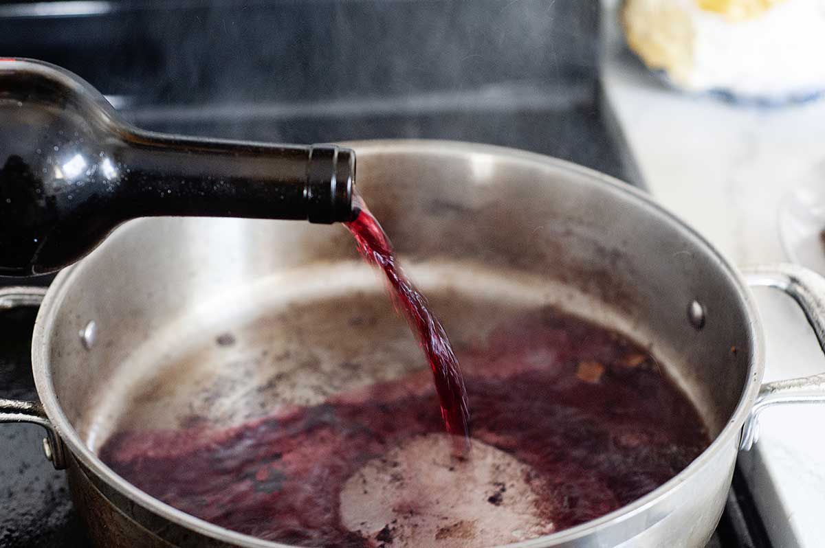 Wine added to a pot to make a braised short rib recipe.