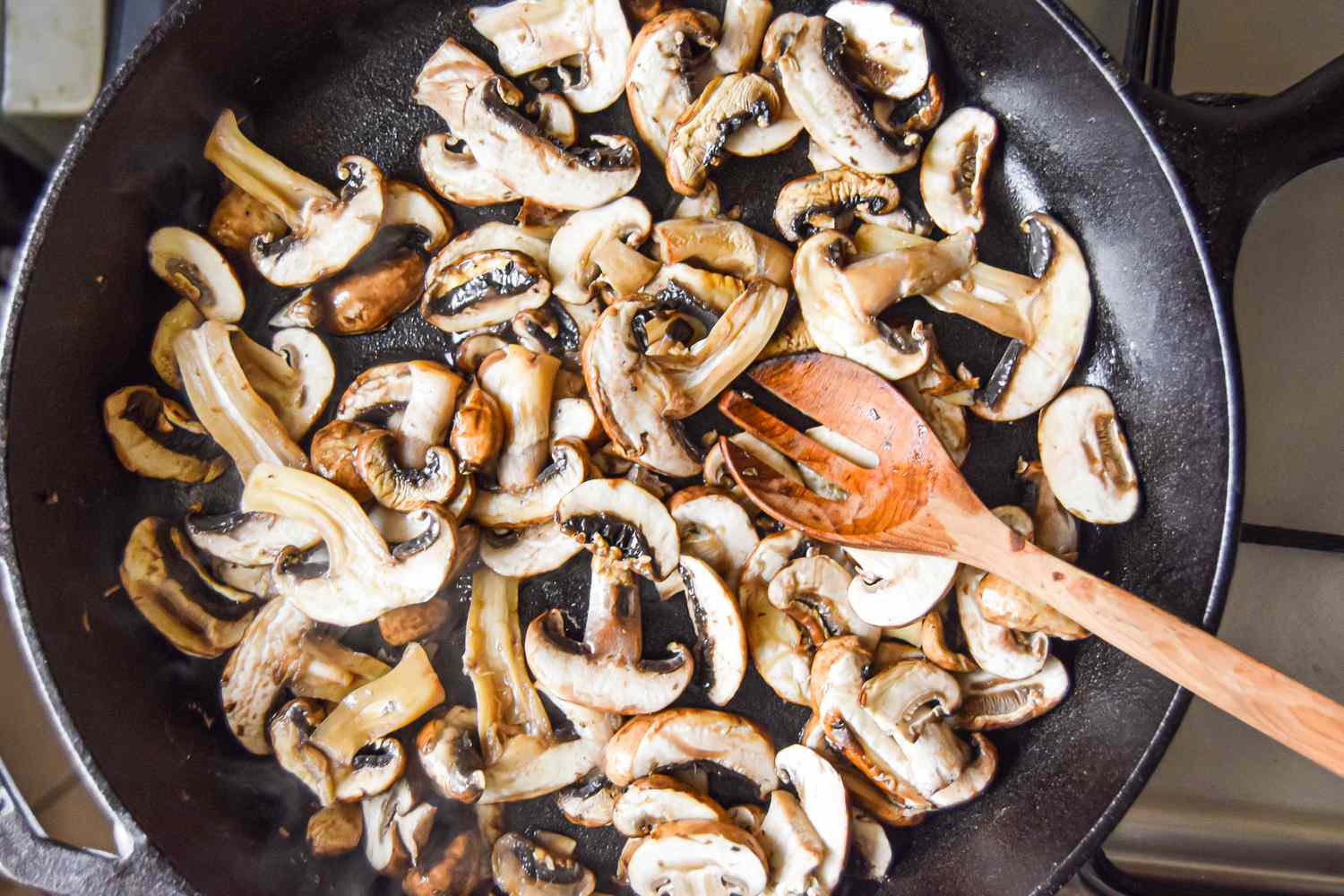 Wooden Spoon Used to Stir Mushrooms in Skillet for A Better Way to Cook Mushrooms