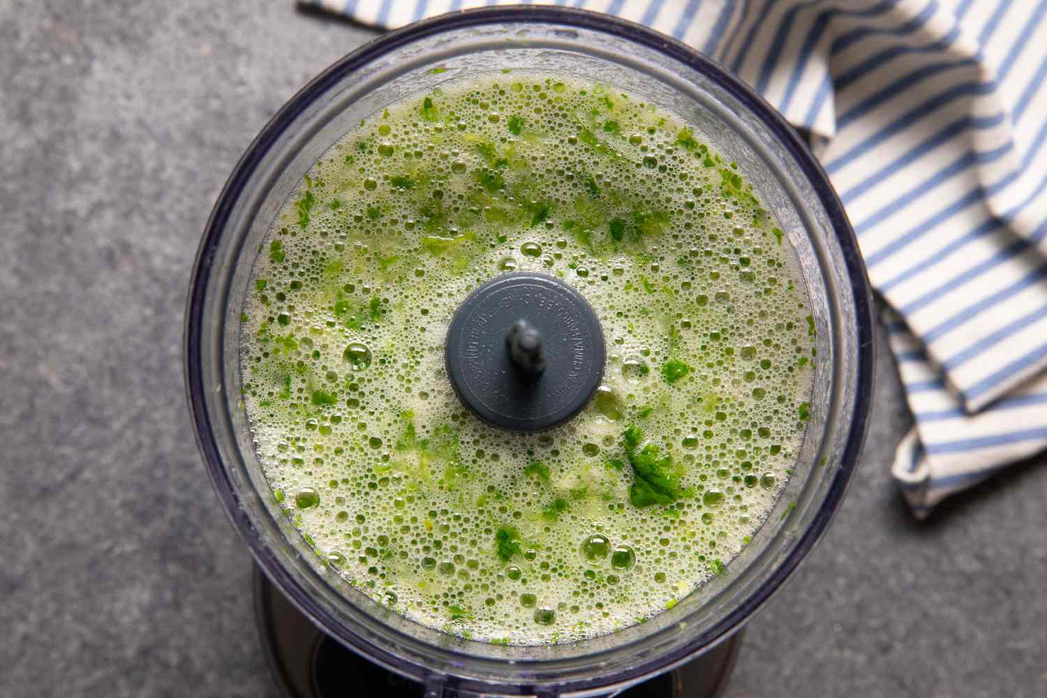 Cilantro Marinade in the Food Processor Next to a Blue and White Stripped Kitchen Towel for Arrachera (Mexican Skirt Steak) Recipe