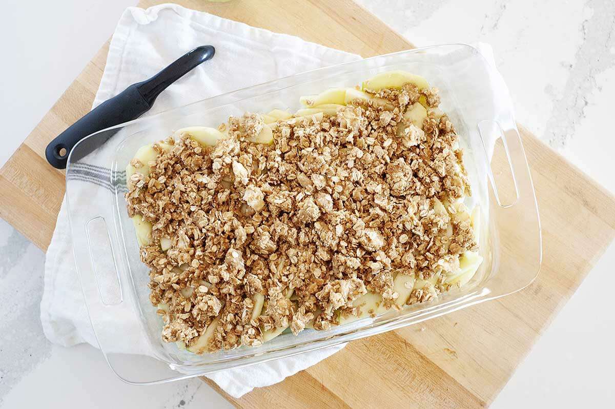 Sliced apples topped with apple crisp topping for the best apple crisp.