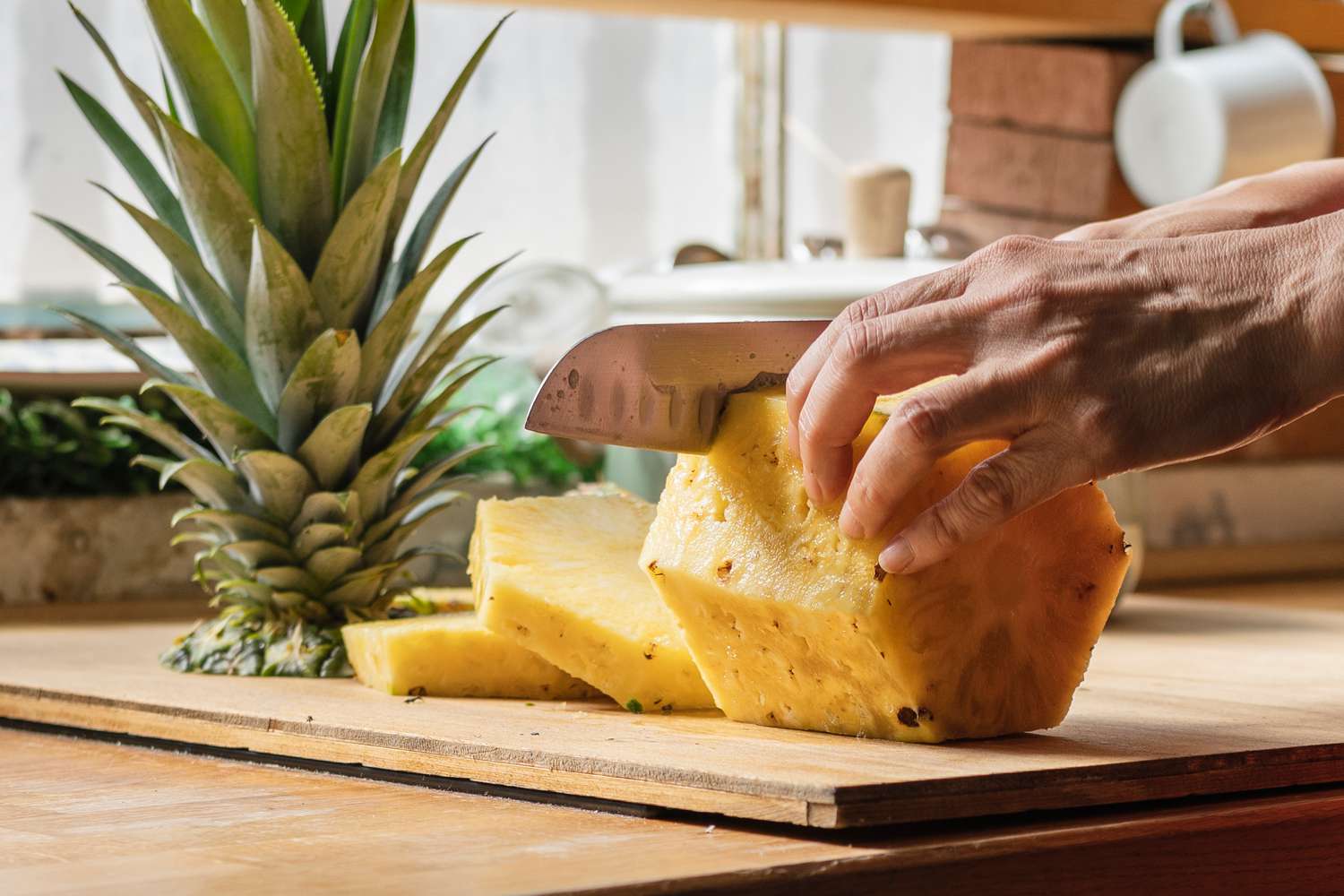someone cutting a pineapple on a cutting board