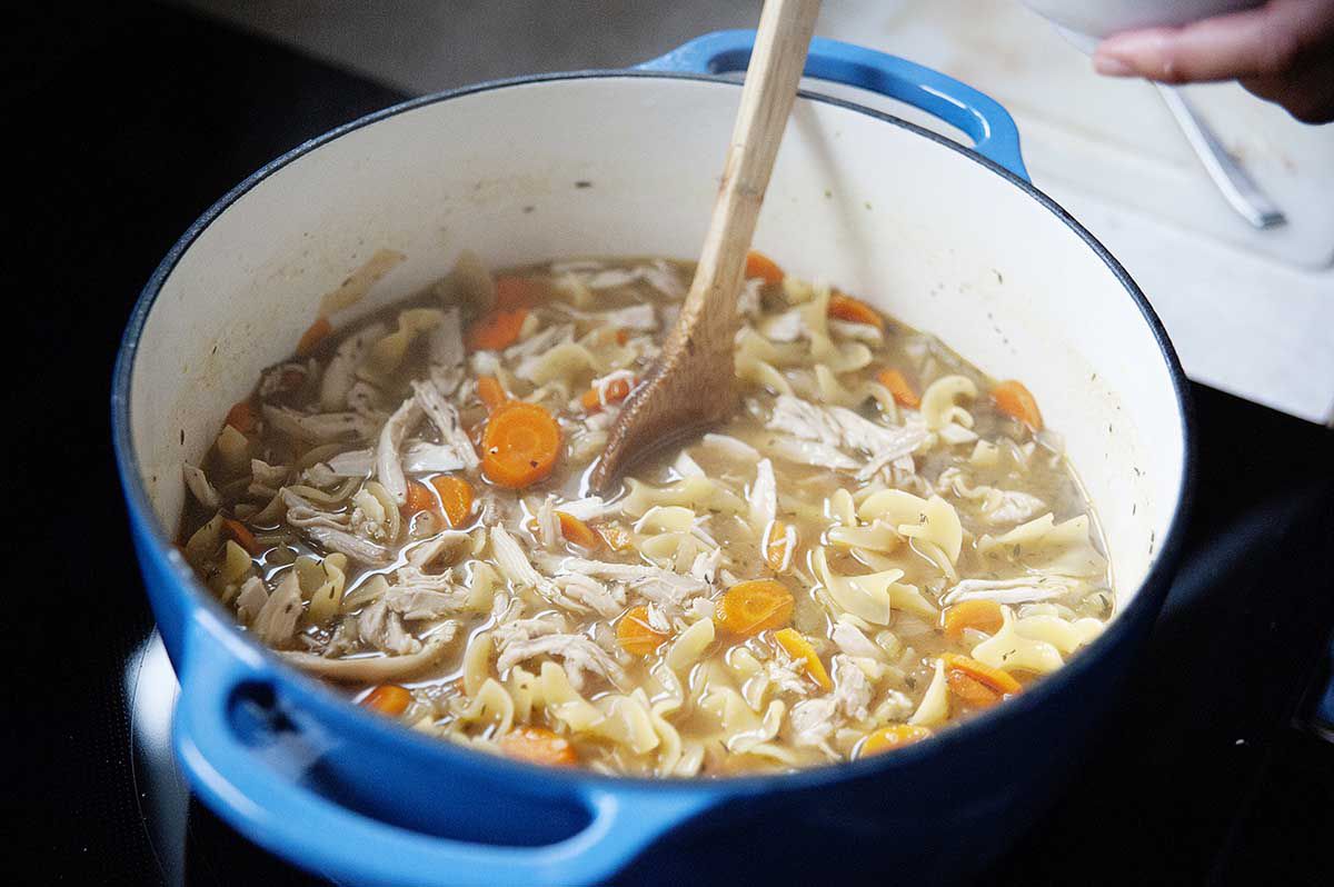 A blue pot full of homemade chicken noodle soup.
