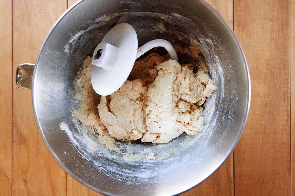 A dough hook rests in a metal bowl with the dough for a homemade king cake.