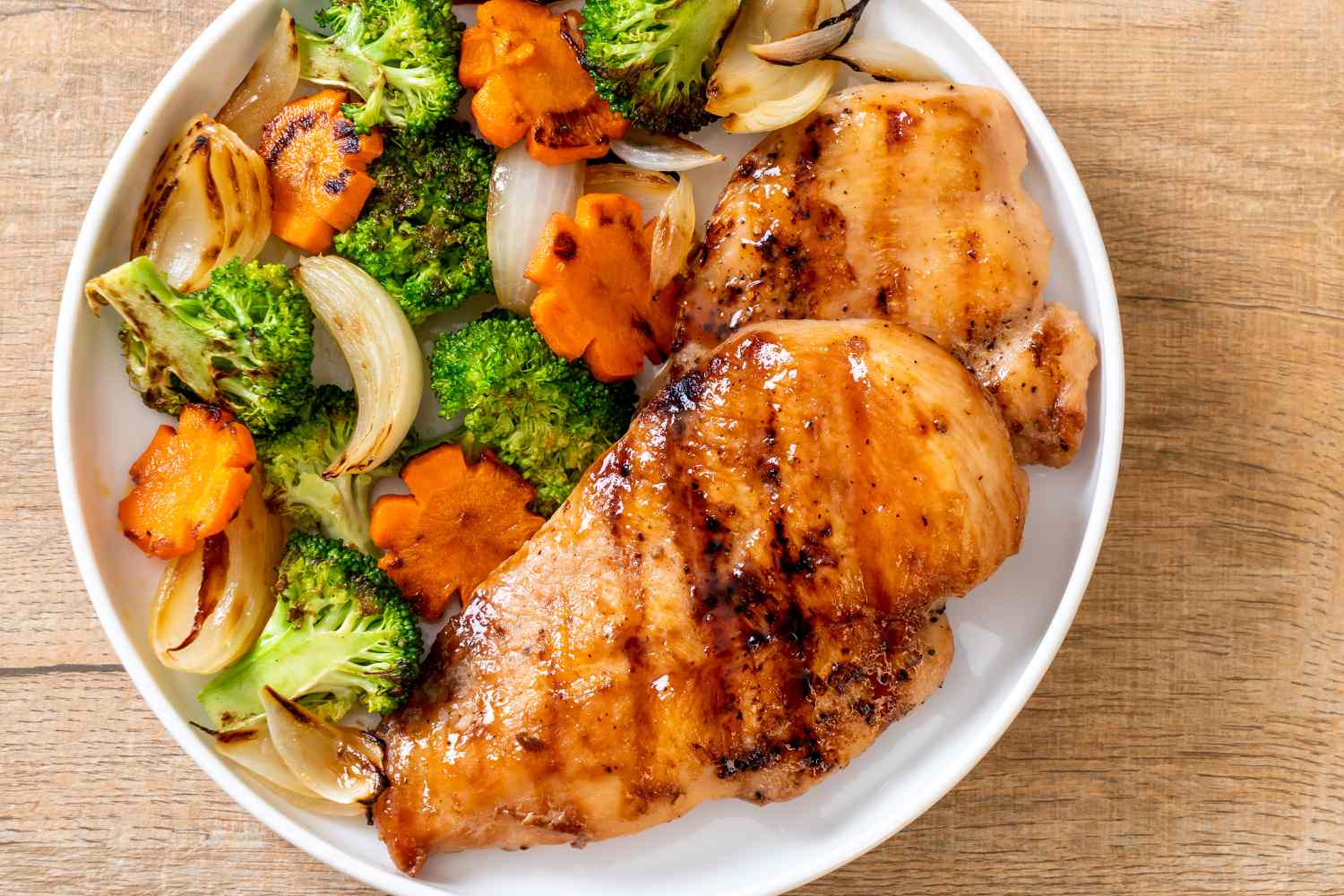 Grilled chicken breasts on a plate with grilled veggies