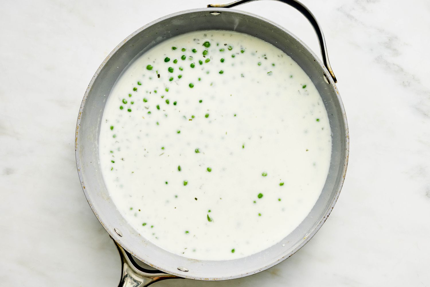 Peas and cream added to skillet for Sliced bacon cooked in a skillet for Skillet Gnocchi recipe