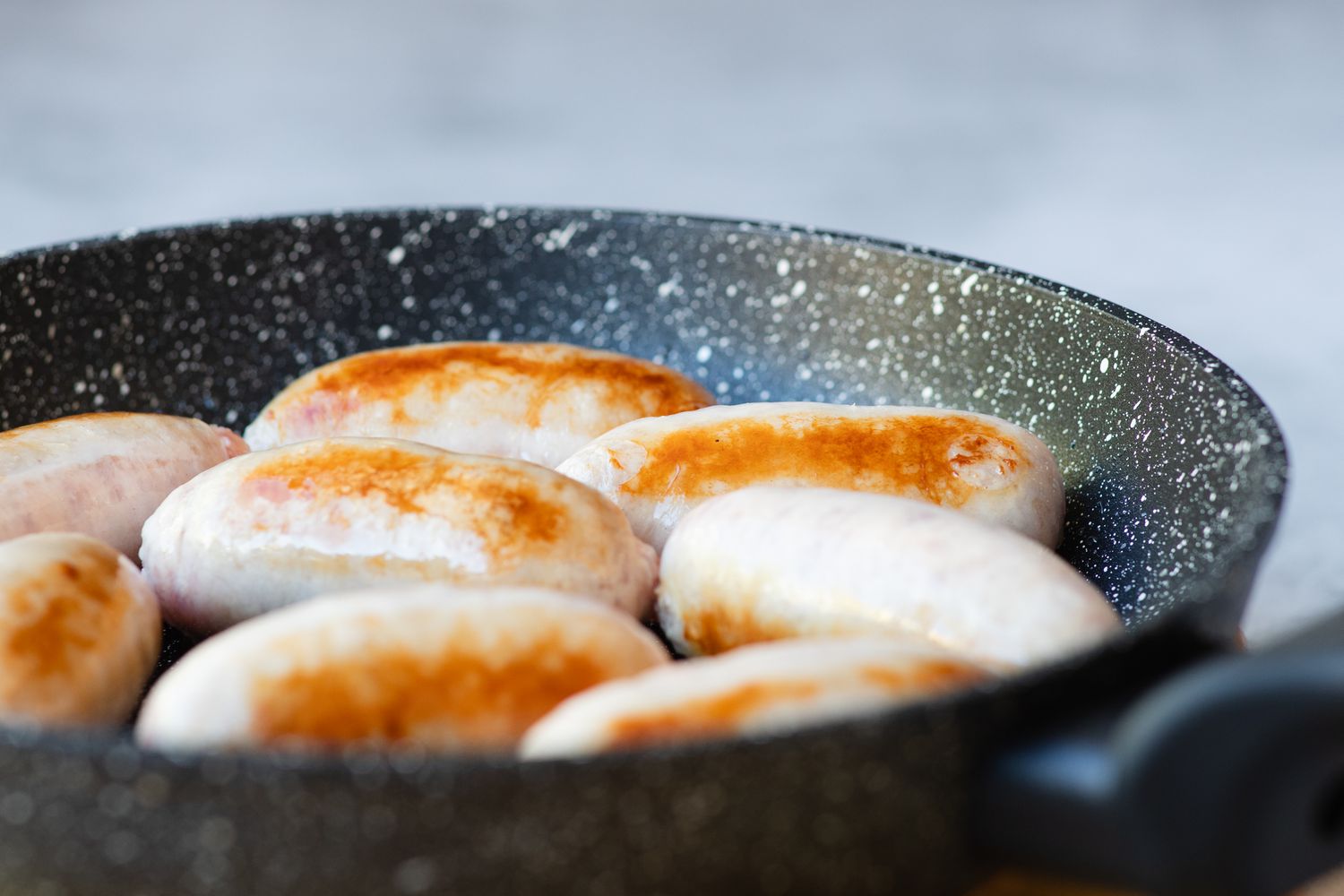 Cooking english sausages in a skillet.