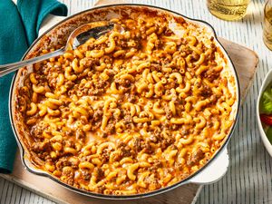 homemade hamburger helper in a skillet at a table setting with two glasses of soda and a side salad