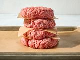 Stack of uncooked hamburger patties on parchment paper