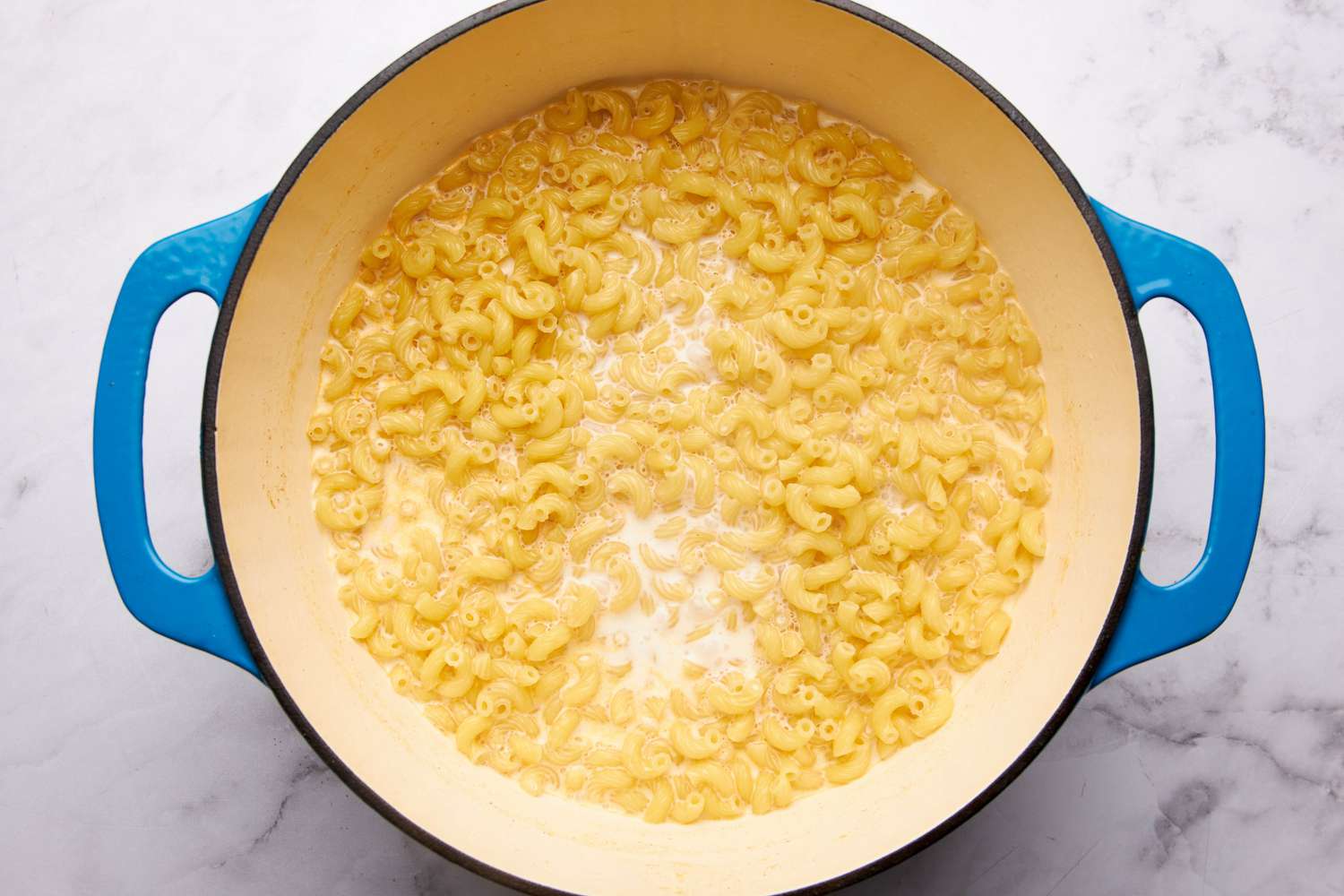 Macaroni boiling in the water and half & half mixture in the dutch oven for macaroni and cheese one pot recipe 