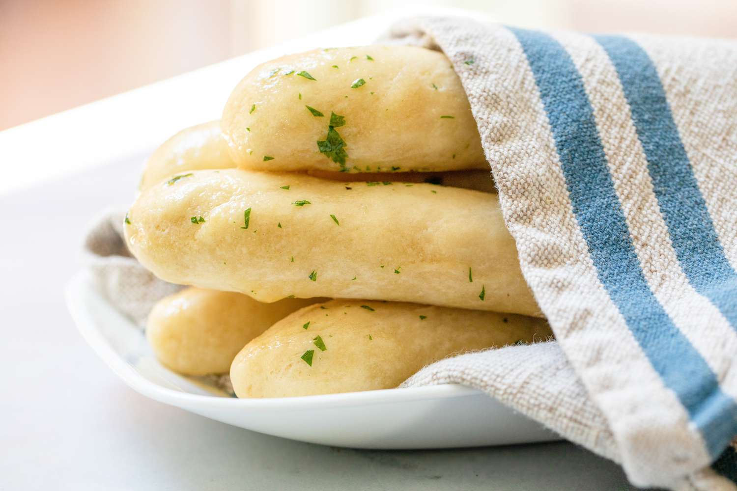 Breadsticks with Garlic Butter on a Plate Covered with a Kitchen Towel