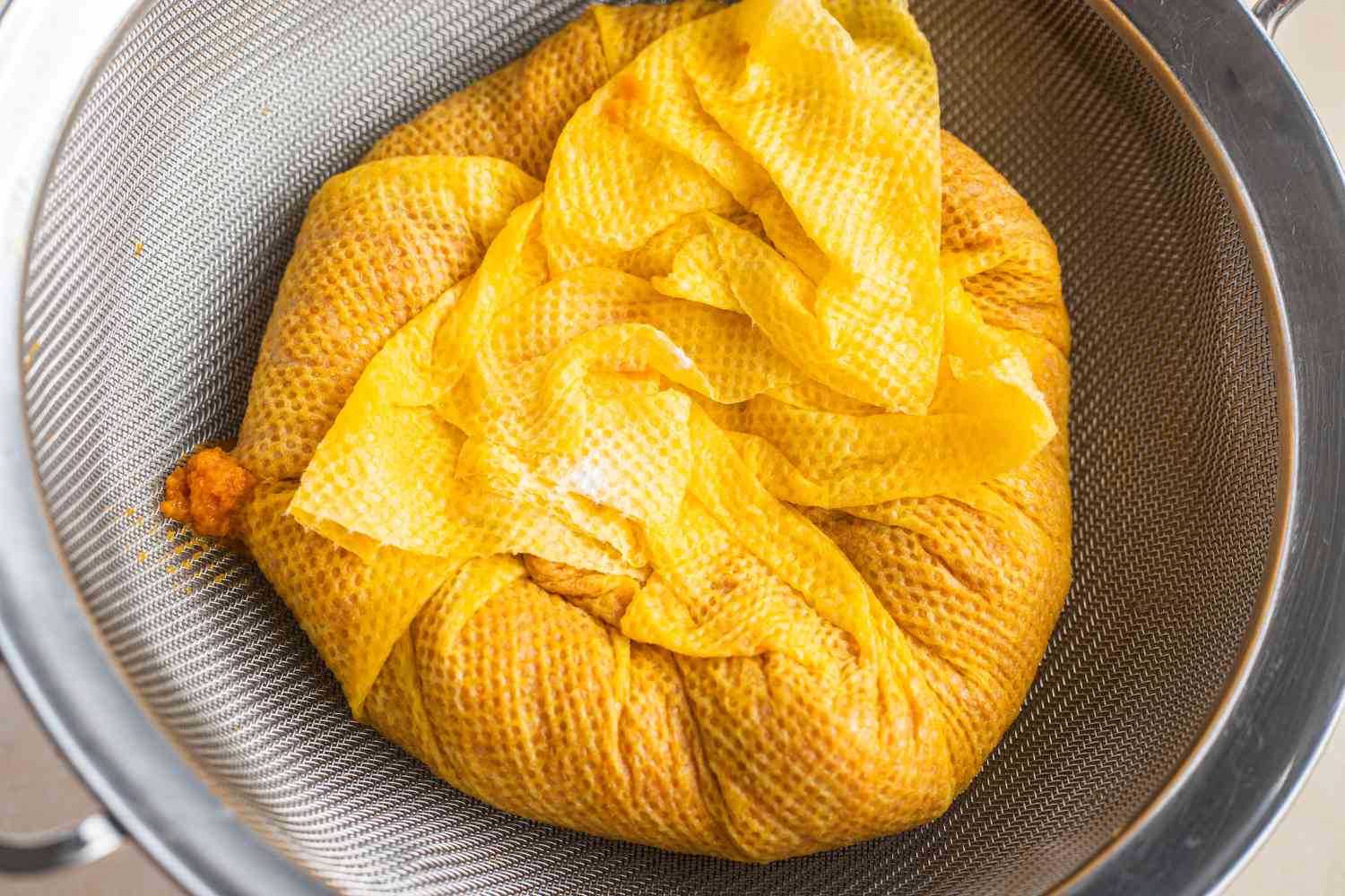 Pumpkin Puree Drained in Layer of Paper Towels Over a Colander for Pumpkin Ladoo Recipe