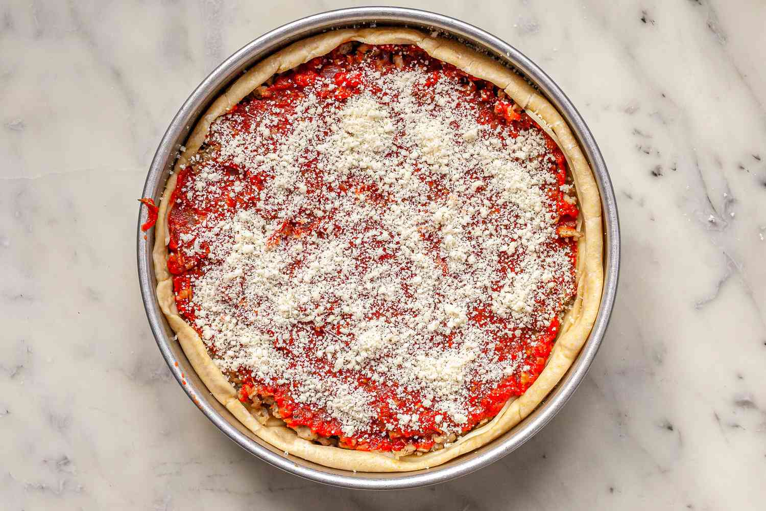 Parmesan sprinkled on Homemade Chicago-Style Deep Dish Pizza before baking.