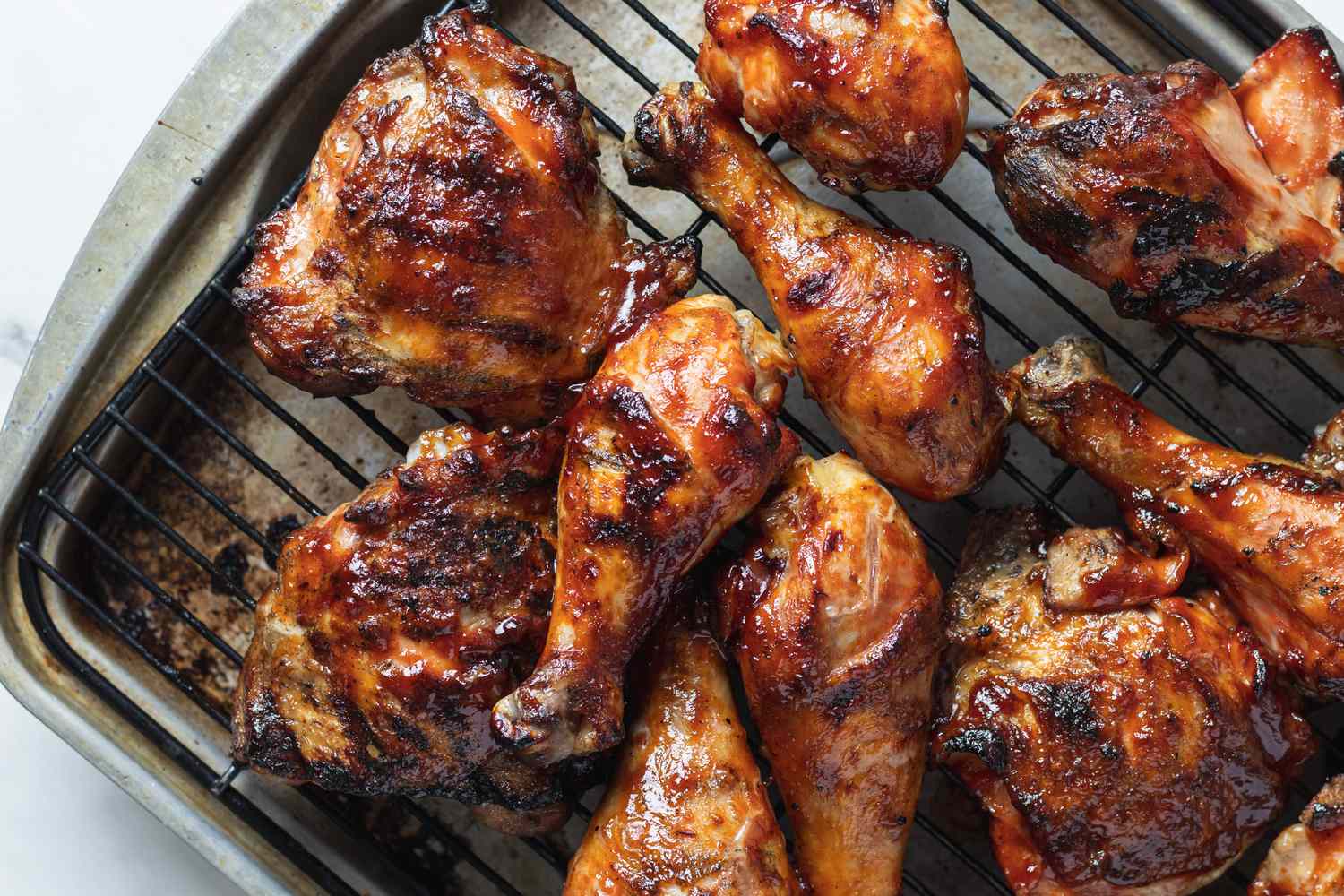 Overhead view of grilled chicken thighs on a cooling rack.