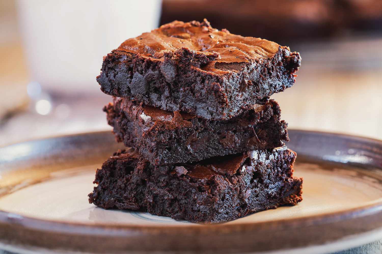 Three fudgy brownies stacked on a plate